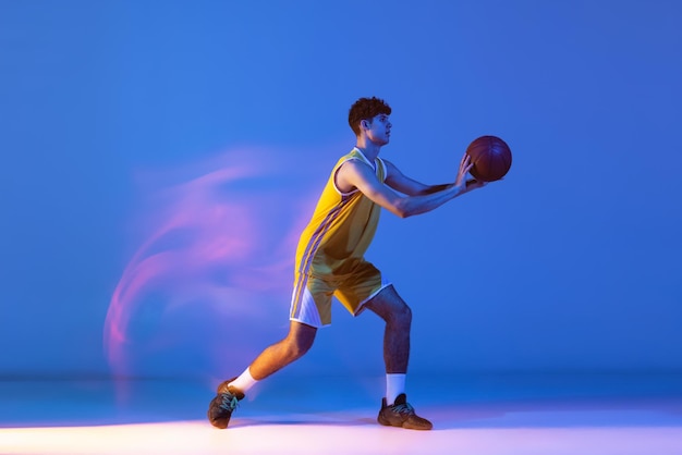 Basket-ball de formation de jeune homme sportif isolé sur dégradé en néon. Faire de la vaisselle exercice