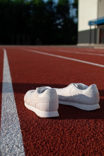 Baskets athlétiques blanches sur un tapis roulant de stade. Concepts de sport, de santé et de bien-être.