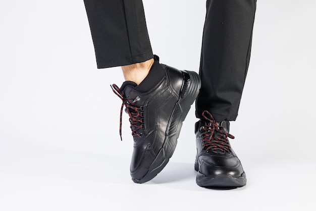 Baskets d'automne pour hommes en cuir noir élégant sur fond blanc sur les jambes des hommes. Baskets collection hiver 2022.