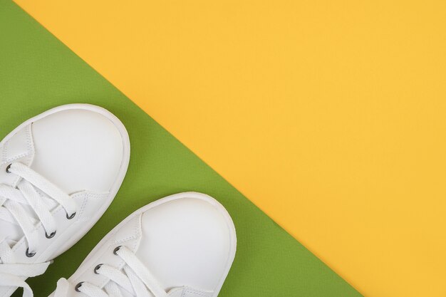 Baskets blanches à lacets sur un sol vert et jaune