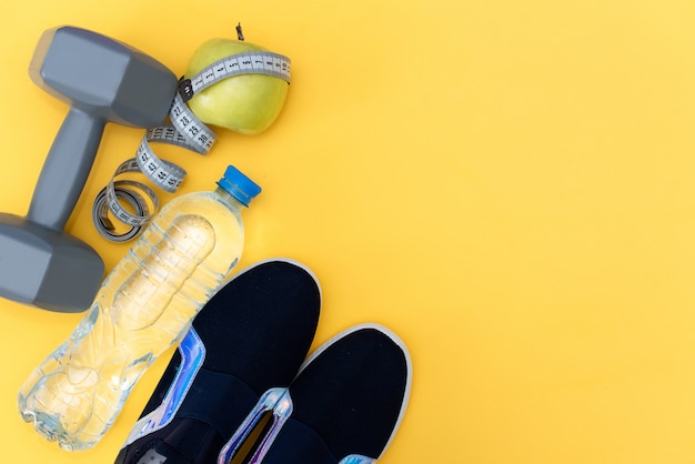 Baskets bleus et bouteille d&#39;eau sur fond jaune.