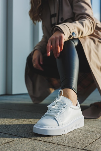 Baskets en cuir pour femmes blanches à la mode élégantes sur le trottoir par une journée ensoleillée