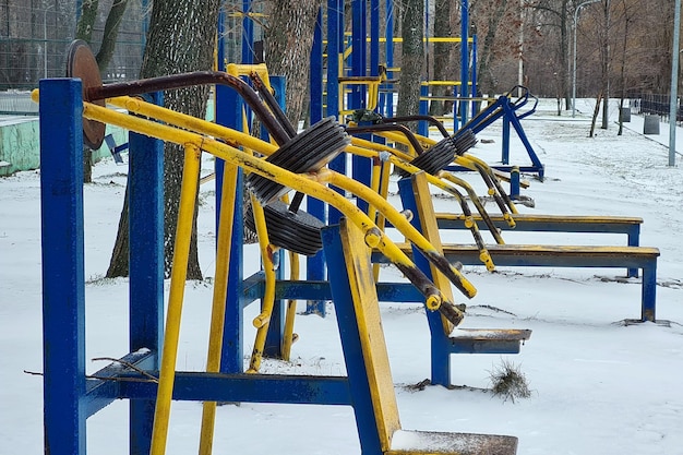 Photo des baskets en fer dans les couleurs jaune et bleue dans un parc de neige d'hiver vide equipement de fitness pour le culturisme