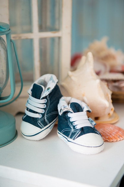 Photo baskets jeans pour enfants à l'intérieur de la mer sur fond de coquillages