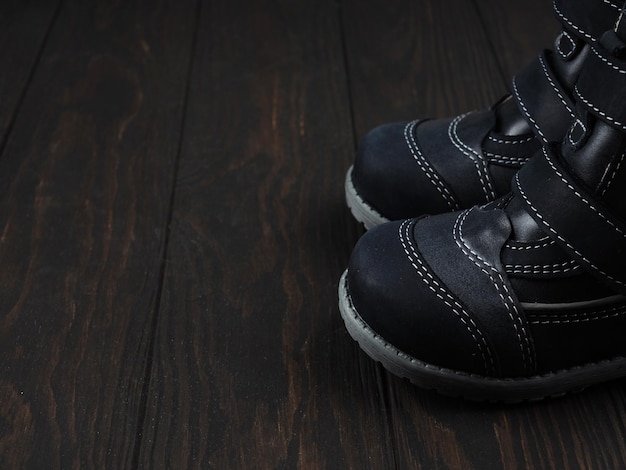 Baskets noires pour enfant sur fond bois, chaussures pour enfants, copie de l'espace.