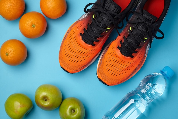 Baskets oranges fruits et bouteille d'eau sur une surface bleue