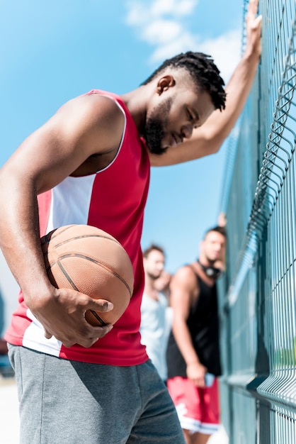 Basketteur afro-américain avec ballon debout près du filet