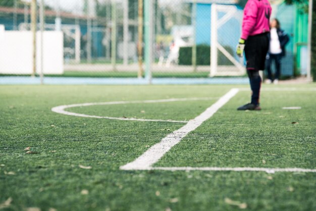 Basse section du gardien de but masculin debout sur le terrain de football