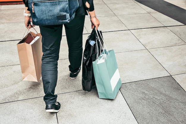 Basse section de la femme avec des sacs d'achat marchant sur le trottoir