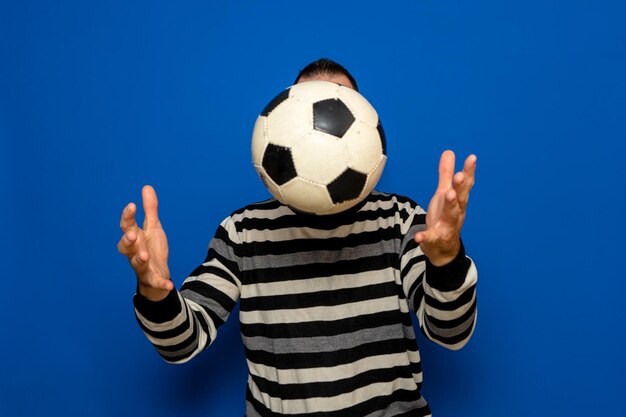 Basse section d'une femme tenant un ballon de football contre un ciel bleu clair