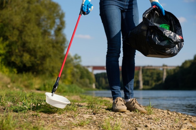 Photo basse section d'une femme tenant un sac en plastique alors qu'elle se tient au bord du lac