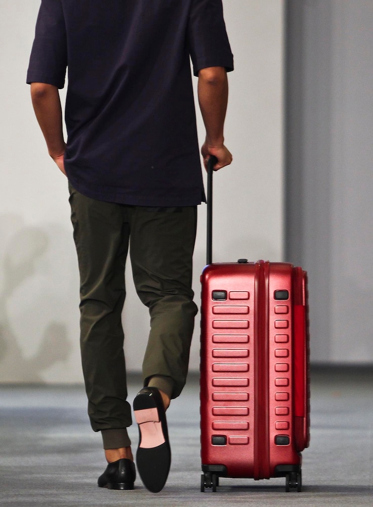 Photo basse section de l'homme avec des bagages marchant sur la route