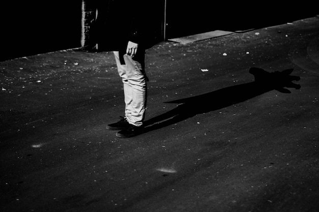 Photo basse section de l'homme debout avec l'ombre sur la route