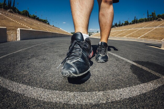 Basse section de l'homme marchant sur une piste de sport au stade