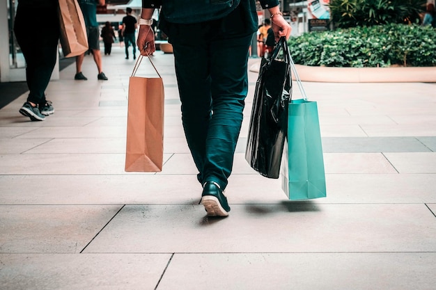Basse section d'homme avec des sacs marchant sur le trottoir