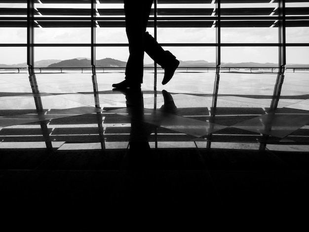 Basse section de l'homme silhouette marchant sur le sol brillant