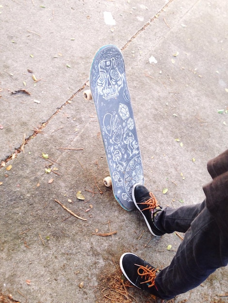 Photo basse section de l'homme avec skateboard sur le sol