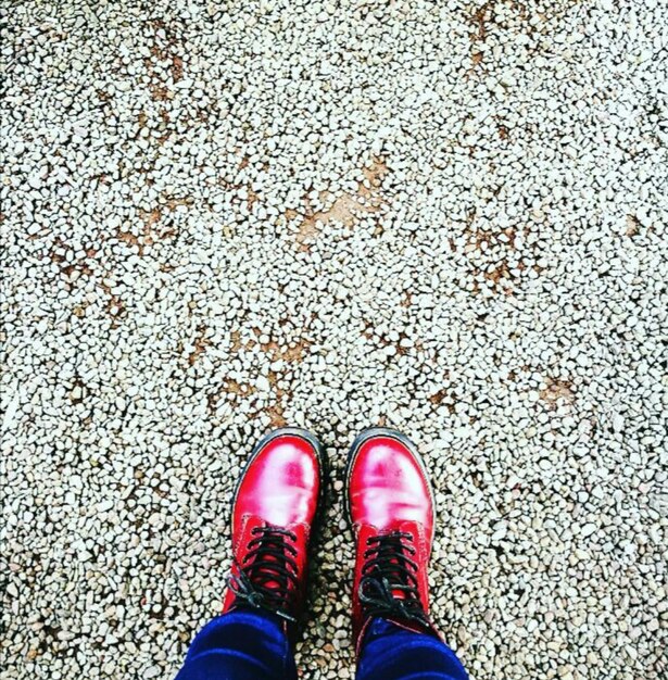Photo basse section de la personne portant des chaussures rouges sur le sol