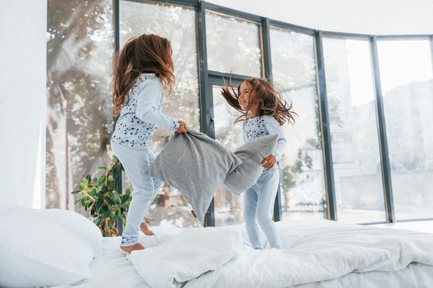 Bataille d'oreillers Deux jolies petites filles à l'intérieur à la maison ensemble Enfants s'amusant