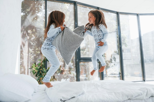 Bataille d'oreillers Deux jolies petites filles à l'intérieur à la maison ensemble Enfants s'amusant