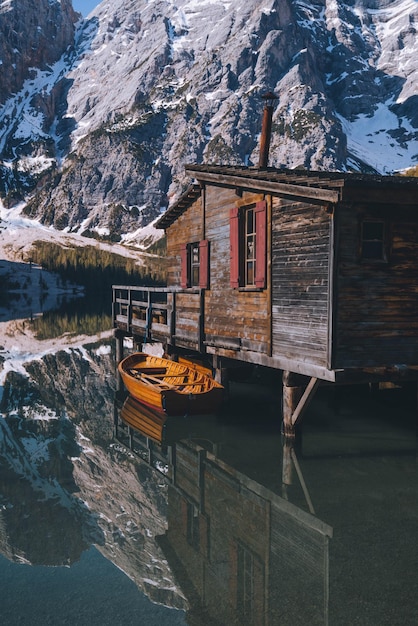 Un bateau amarré par une cabane en bois contre une montagne enneigée.