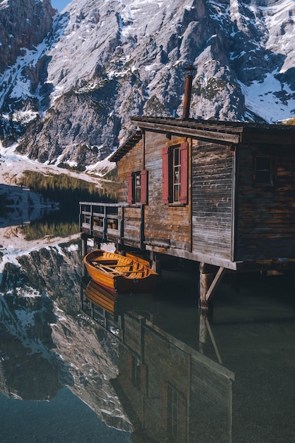 Photo un bateau amarré par une cabane en bois contre une montagne enneigée.