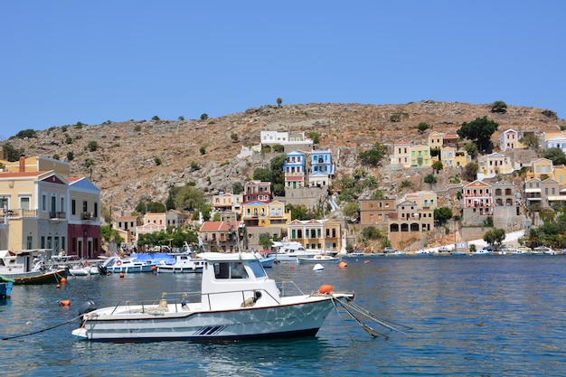Bateau blanc dans le port de l'île grecque de Symi avec front de mer sur l'arrière-plan