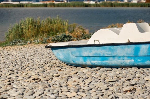 Bateau bleu sur une plage de galets sur fond de mer