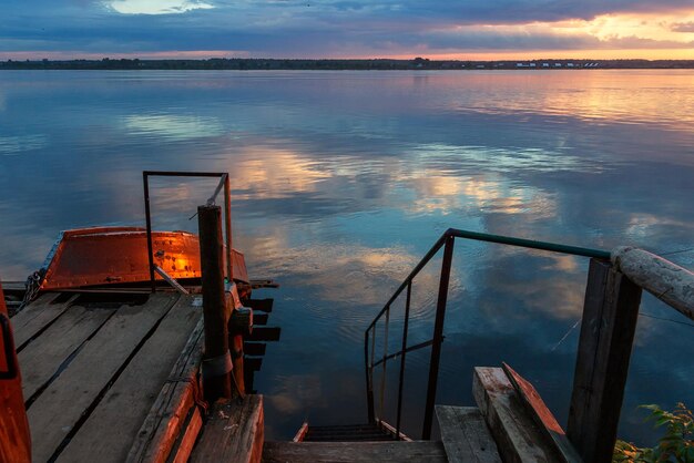 Bateau en bois amarré au quai du port pour des promenades sur la rivière Ancien escalier en bois descendant au lac Coucher de soleil sur la rivière