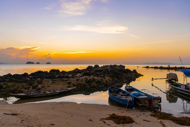 Bateau en bois au large d'une île tropicale. Soirée, coucher de soleil dans l'océan. Paysage tropical. Les vagues de lumière secouent le bateau