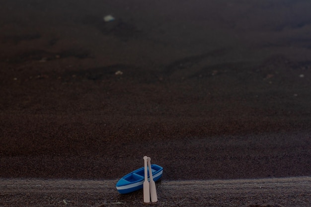 Le bateau en bois bleu se tient sur le rivage avec des avirons