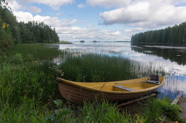 Bateau en bois jaune sur la rive d'un lac pittoresque et reflet des nuages