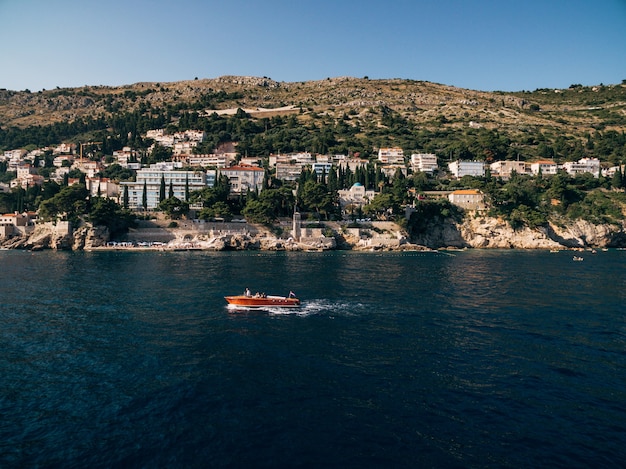 Bateau en bois de luxe avec un moteur navigue sur le fond de la côte près de la vieille ville de Dubrovnik