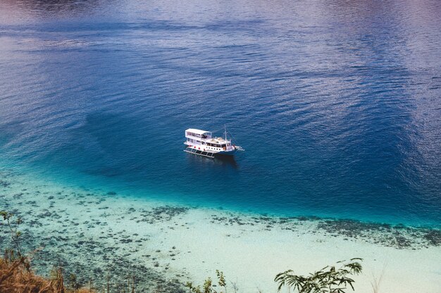 Bateau en bois phinisi blanc naviguant sur une mer magnifique avec de l'eau bleue transparente