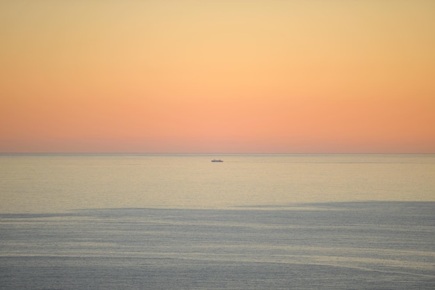 Bateau dans la mer sur la ligne d'horizon fond de ciel dégradé doré ville de Fuji Japon