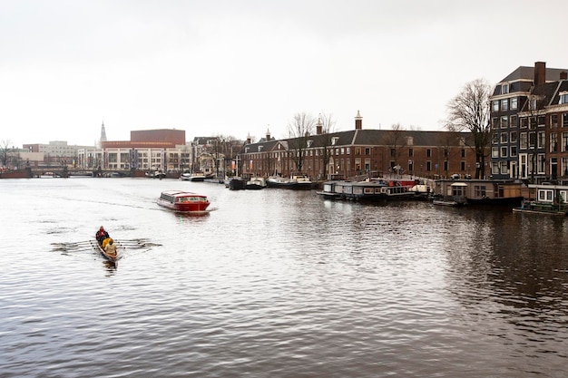 Un bateau descend une rivière avec une personne à l'arrière à Amsterdam