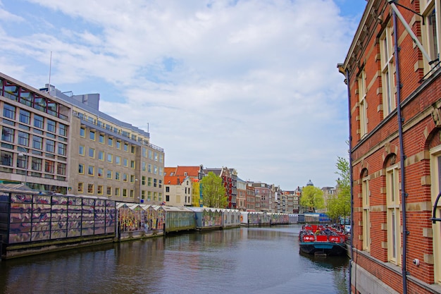 Bateau à eau dans le canal de la rivière Amstel et bâtiments à remblai, Amsterdam, Pays-Bas.