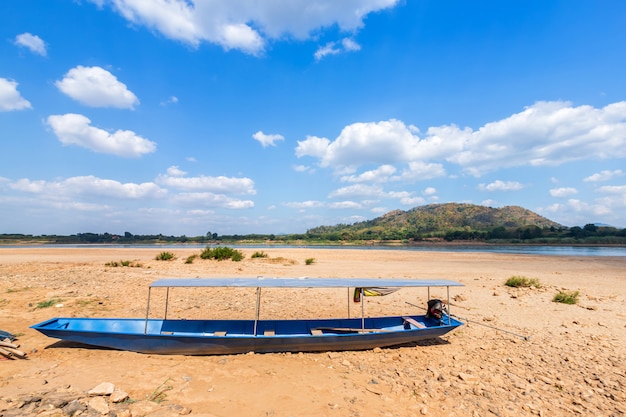 Bateau garé dans le sol de sable sec de la rivière Mae Khong avec vue sur la montagne du Laos aux rapides de Kaeng Khud Khu à Chiang Khan