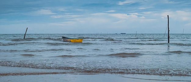 un bateau jaune est attaché à un pieu sur la plage