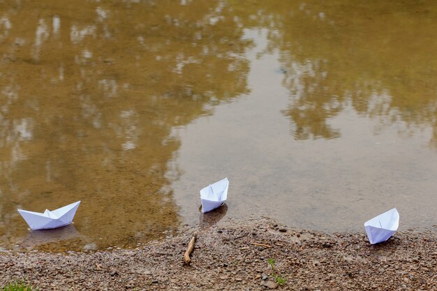 Bateau jouet en papier blanc sur l'eau bleue près du rivage