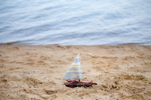 Un bateau jouet sur une plage de sable, un voilier jouet sur le sable contre la mer