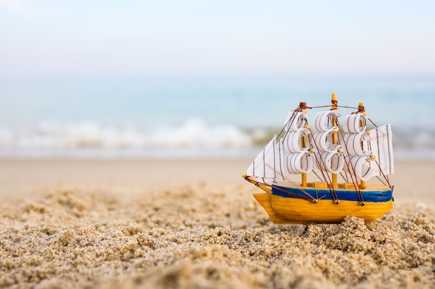 Bateau jouet sur le sable au bord de la mer. Concept de vacances d'été