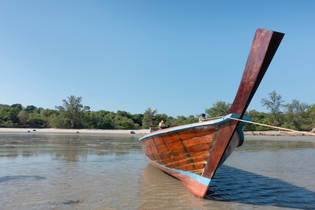 Bateau longtail traditionnel en bois thaïlandais et belle plage de sable.