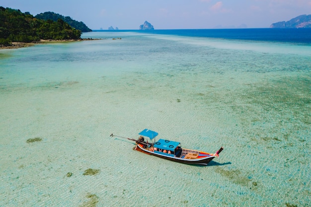 Un bateau à longue queue dans l'océan de couleur turquoise avec des eaux claires à Koh Kradan, en Thaïlande