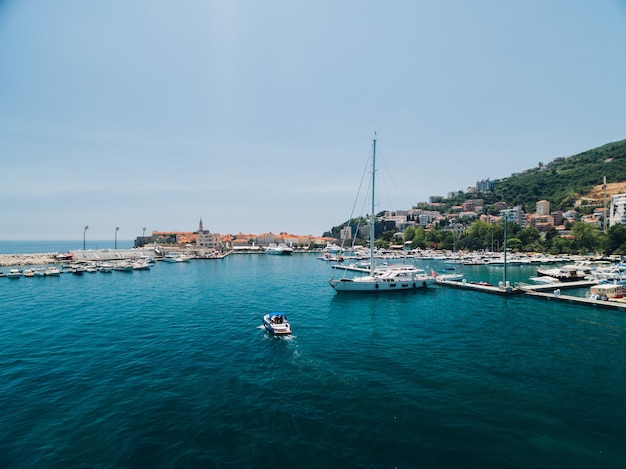 Bateau à moteur blanc navigue au-delà de la jetée de la ville de Budva Monténégro