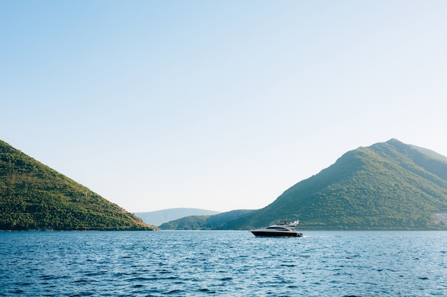 Le bateau à moteur flotte sur l'eau chaude journée ensoleillée dans la ville de Perast