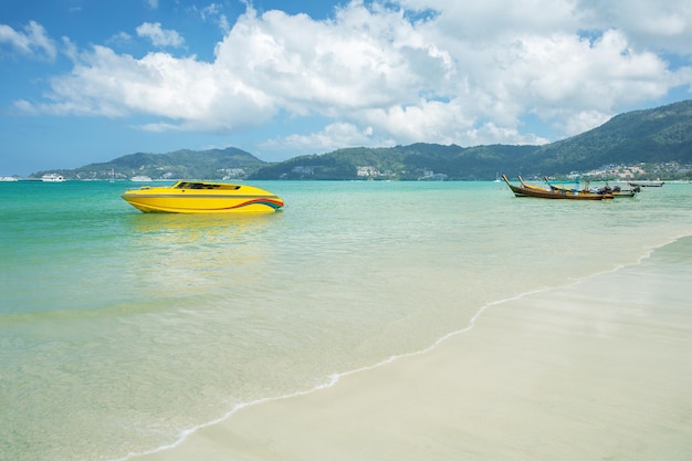 Bateau à moteur jaune et longs bateaux thaïlandais dans la mer sur la plage de Patong Phuket Thaïlande Île tropicale avec plage de sable blanc paradisiaque et eau claire turquoise