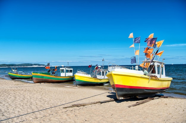 Bateau ou navire de pêche maritime avec des drapeaux colorés au mouillage sur la plage par beau temps sur fond bleu de la mer et du ciel