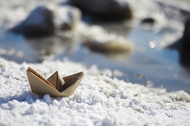 Bateau en papier dans l'eau dans la rue. Le concept du début du printemps. La fonte des neiges et un bateau en origami sur les vagues de l'eau.