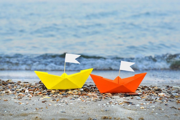 Photo bateau en papier en mer plage voilier en papier origami prêt à naviguer sur l'eau bleue concept de voyage insolite